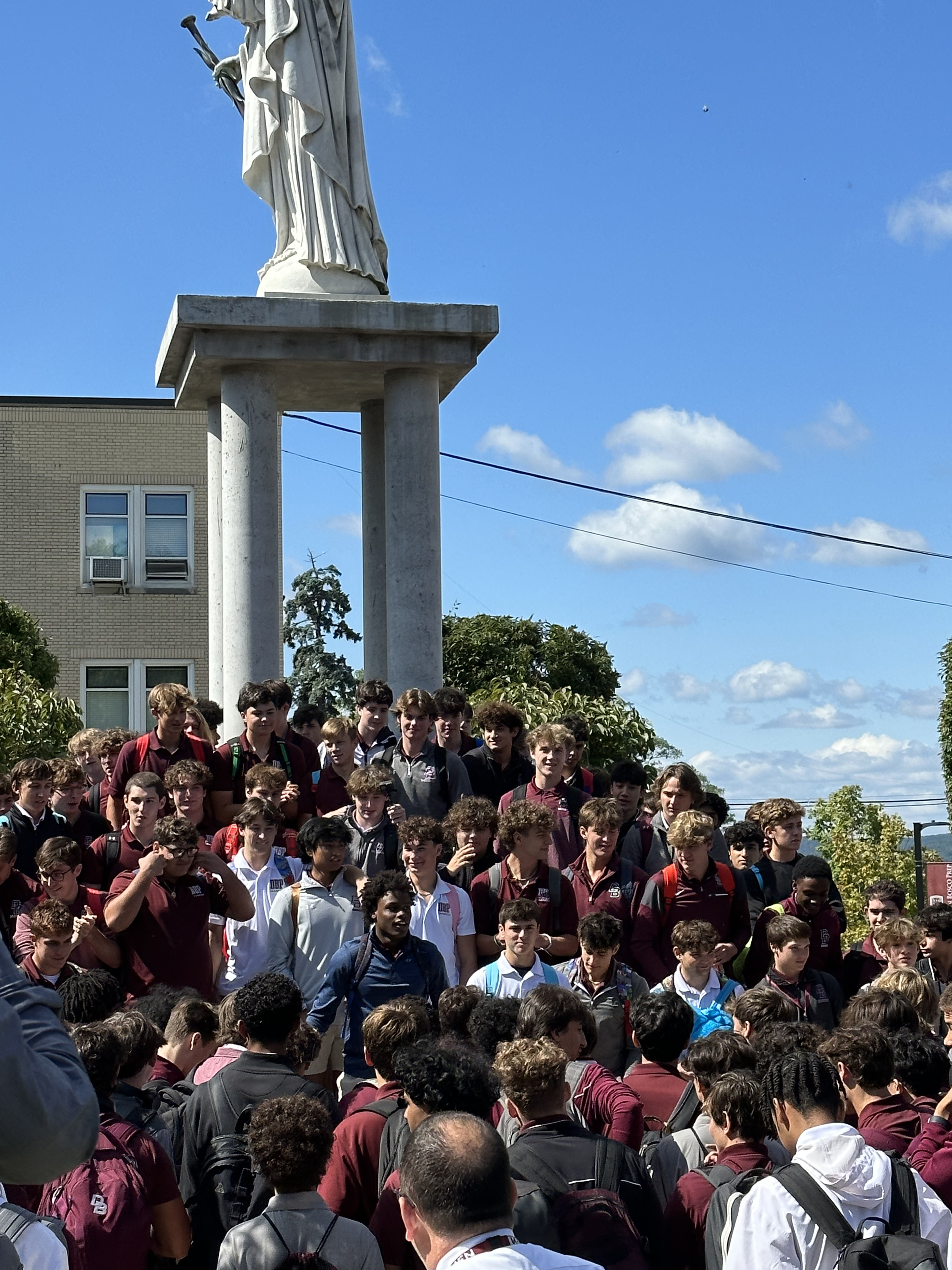 Don Bosco Students outside gathered by a statue of Mary
